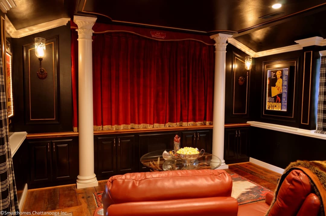 Media room with a large wall-mounted television above a fireplace and a sectional sofa
