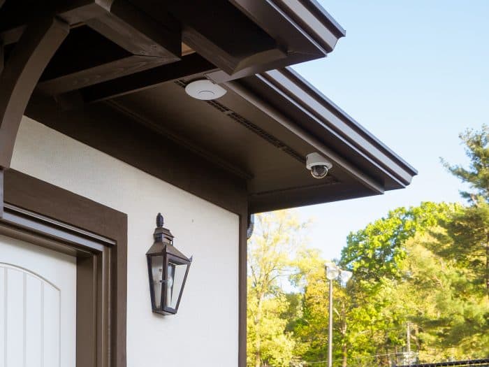 Small security camera mounted under the eave of a house near the front entry