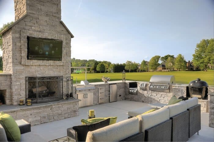 Covered outdoor living area with a television mounted above a stone fireplace