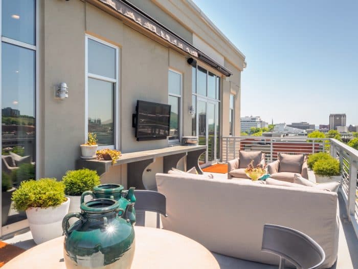 Outdoor television mounted under a roof overhang on a patio with seating